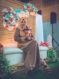 Portrait of woman with bouquet sitting at home during celebration