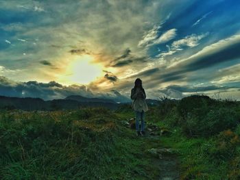 Rear view of woman walking on field against sky