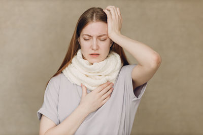 Portrait of young woman standing against wall