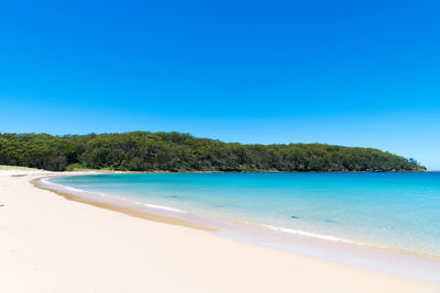 Scenic view of beach against clear blue sky