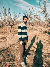 Man standing by bare tree and plants