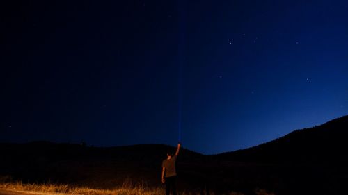 Man standing on field against sky at night