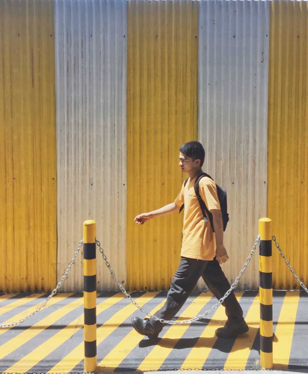 full length, lifestyles, casual clothing, yellow, leisure activity, childhood, standing, rear view, wall - building feature, indoors, holding, built structure, day, front view, sunlight, men, wood - material