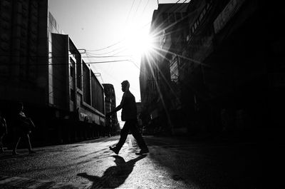 Side view of silhouette man walking on street in city