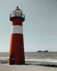 Lighthouse by sea against sky