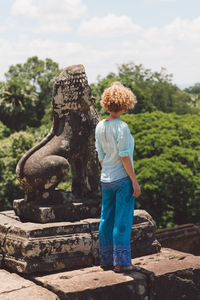 Woman standing by old ruin statue