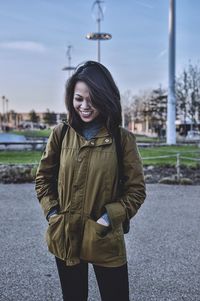 Portrait of smiling young woman standing against sky