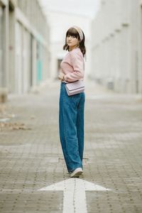 Portrait of young woman standing on footpath