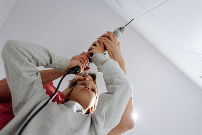 High angle view of father and daughter drilling the wall at home