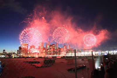 Firework display over river against sky