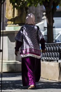 Rear view of woman walking on footpath