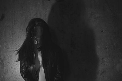 Portrait of young woman standing against wall