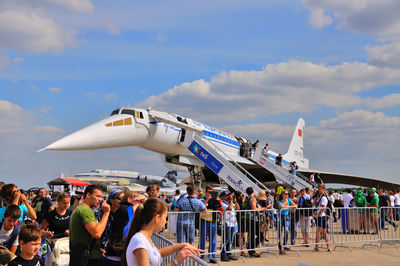 People at airport runway against sky
