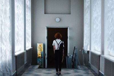 Rear view of woman standing against door at home