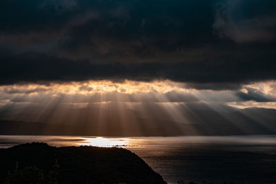 Sunlight streaming through clouds over sea