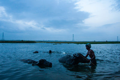 Side view of man sitting on sea against sky