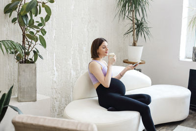 Full length of woman sitting on sofa at home