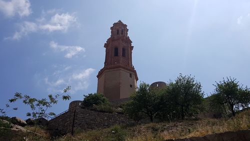 Low angle view of trees and building against sky