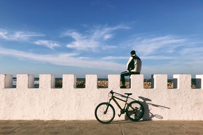 Man standing on bicycle against wall