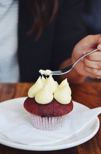 Cropped shot of a persons hand holding a fork tasting a red velvet cupcake 