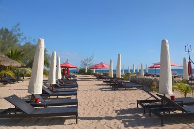 Chairs on footpath against clear blue sky