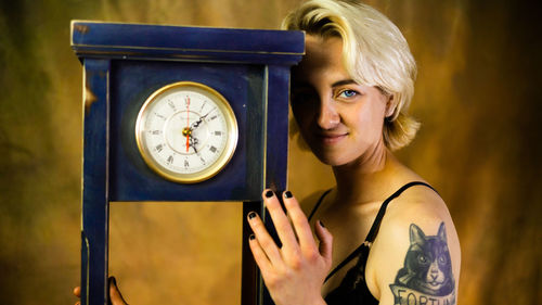 Portrait of young woman holding clock