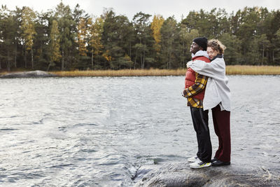 Couple standing by lake and embracing