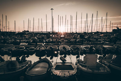 Sailboats moored at harbor against sky during sunset