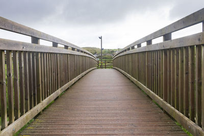 Footbridge over footpath against sky