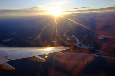Close-up of airplane wing against sky during sunset