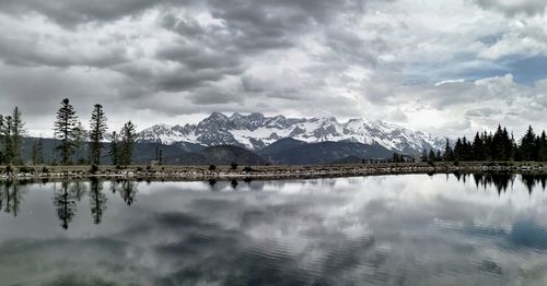 Scenic view of lake by snowcapped mountains against sky