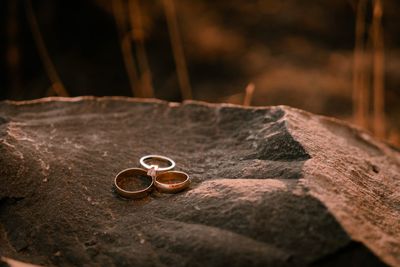Close-up of wedding rings on rock at sunset