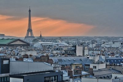 Eiffel tower amidst cityscape during sunset