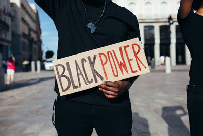 Midsection of man holding text on street in city