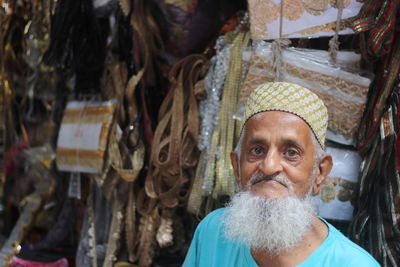 An old muslim man selling goods in his zari shop
