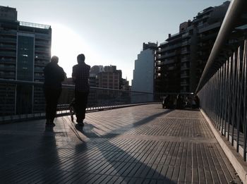 People on elevated walkway in city during sunny day