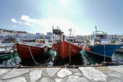Boats moored at harbor against sky