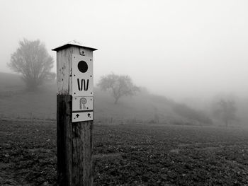 Information sign on field against sky