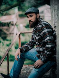 Young man looking away while sitting outdoors