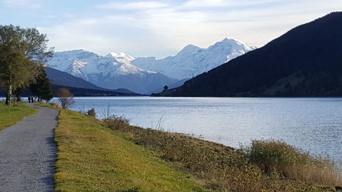 Scenic view of lake by mountains against cloudy sky