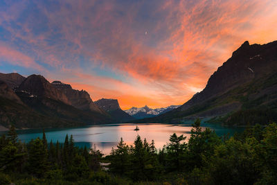 Scenic view of lake by mountains against sky during sunset