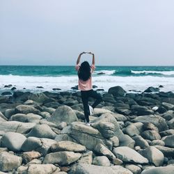 Woman standing in tree pose on rocky shore