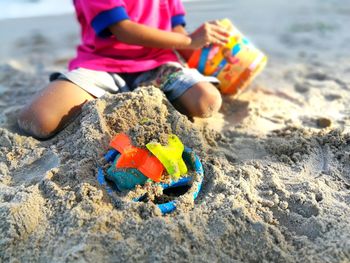 Midsection of boy playing on sand at beach