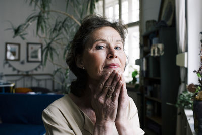 Portrait of senior woman touching face at home