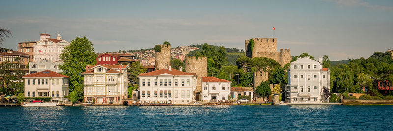 Buildings by river against sky