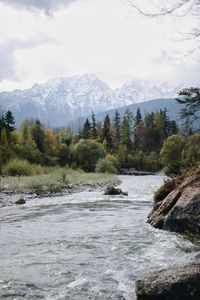 Scenic view of river by mountains against sky