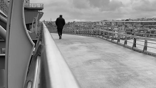 Rear view of man walking on bridge