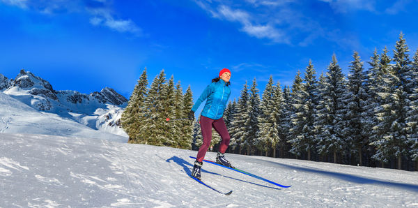 Woman skiing on ice at mountain slope against sky 
