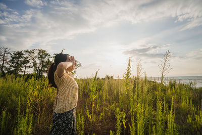 Woman standing amidst plants against sky