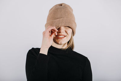 Unaltered candid emotional portrait of young happy blonde long hair woman covering eyes with brown